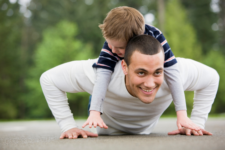 Boy Laying on Man Doing Pushups