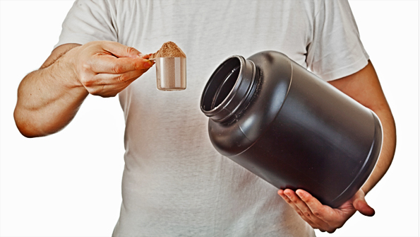 Man preparing his post workout protein shake taking a scoop of c
